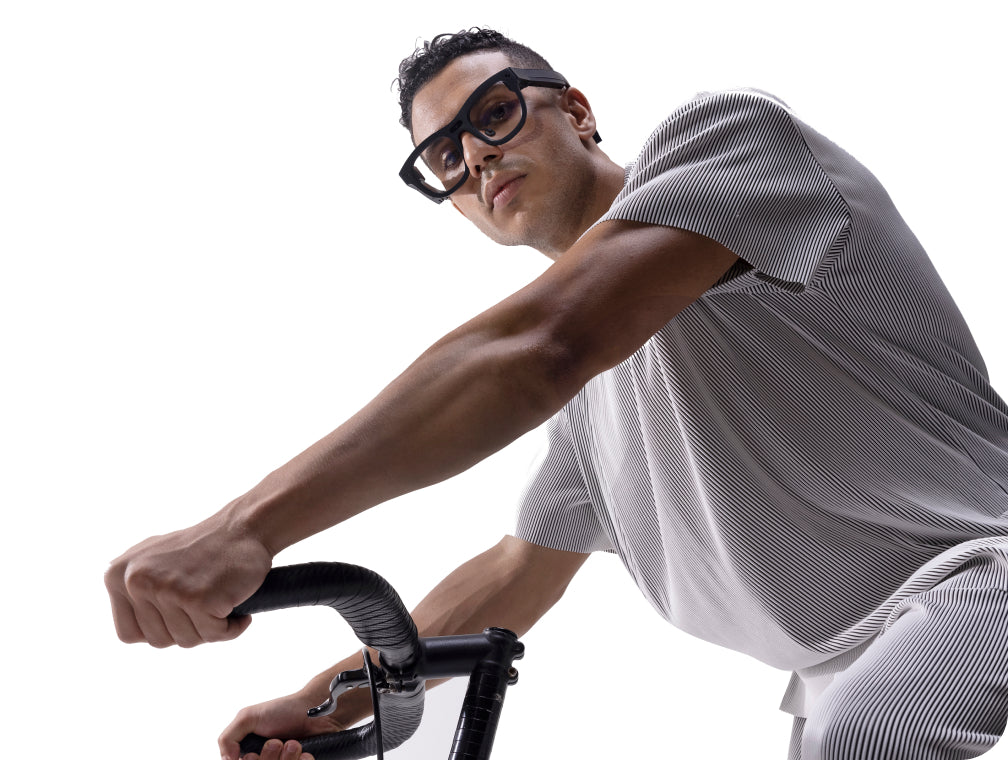 Man riding a road bike while wearing RayNeo X2 smart glasses. RayNeo X2 (discontinued), marketed with "anti-shake filming" for 1080p video.
