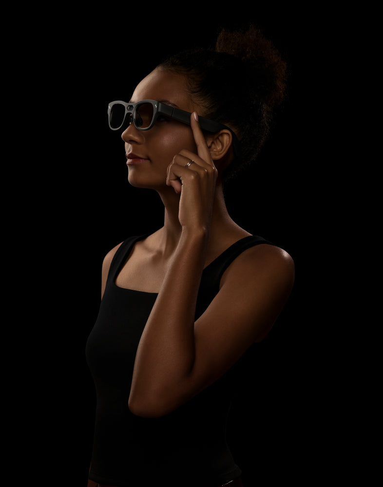 A person wearing gray RayNeo AR glasses in profile, touching the temple arm of the frame with one finger.