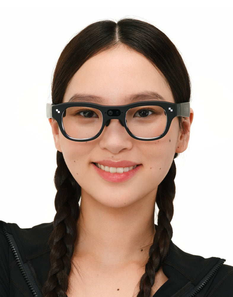 Smiling woman with braided hair wearing black-frame RayNeo smart glasses in a headshot against a white background.